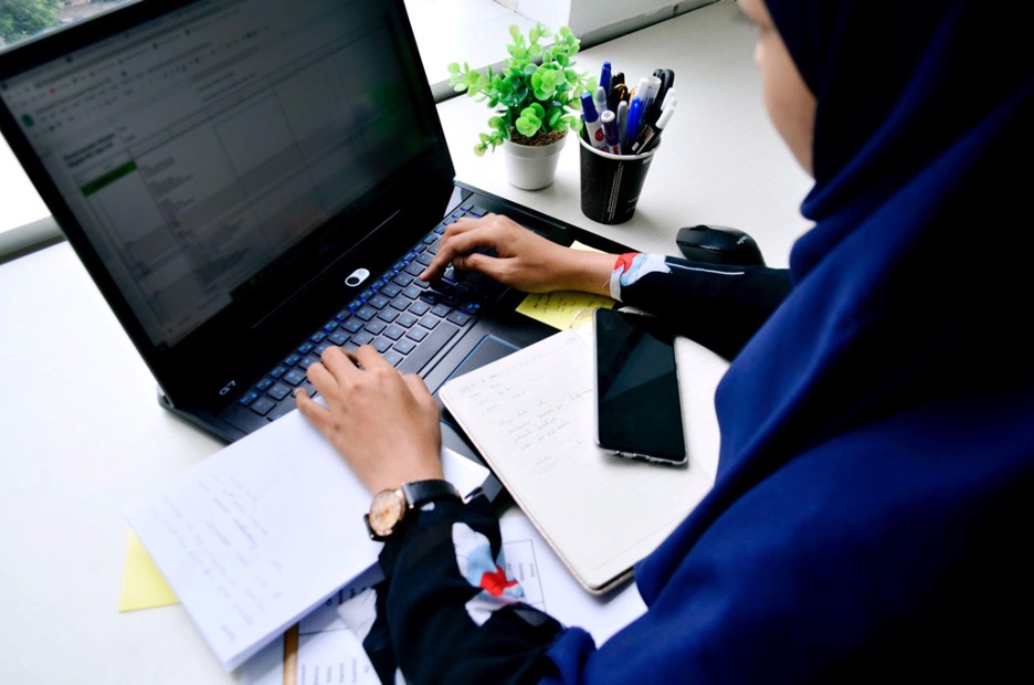This is a photo of a woman working on her laptop with notebooks.